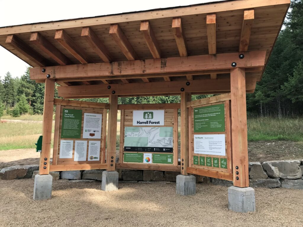 Timber-framed trailhead kiosk displaying maps and information about Harrell Forest
